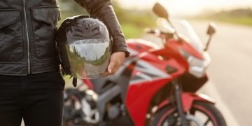 handsome motorcyclist wear leather jacket holding helmet road scaled